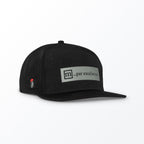 A black trucker hat with a label that reads 'm... par excellence' on the front panel, featuring a small red logo on the side.