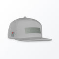 A gray Mint Luxxtrux Par Excellence Trucker Hat with a flat brim and silicone logo on the front.