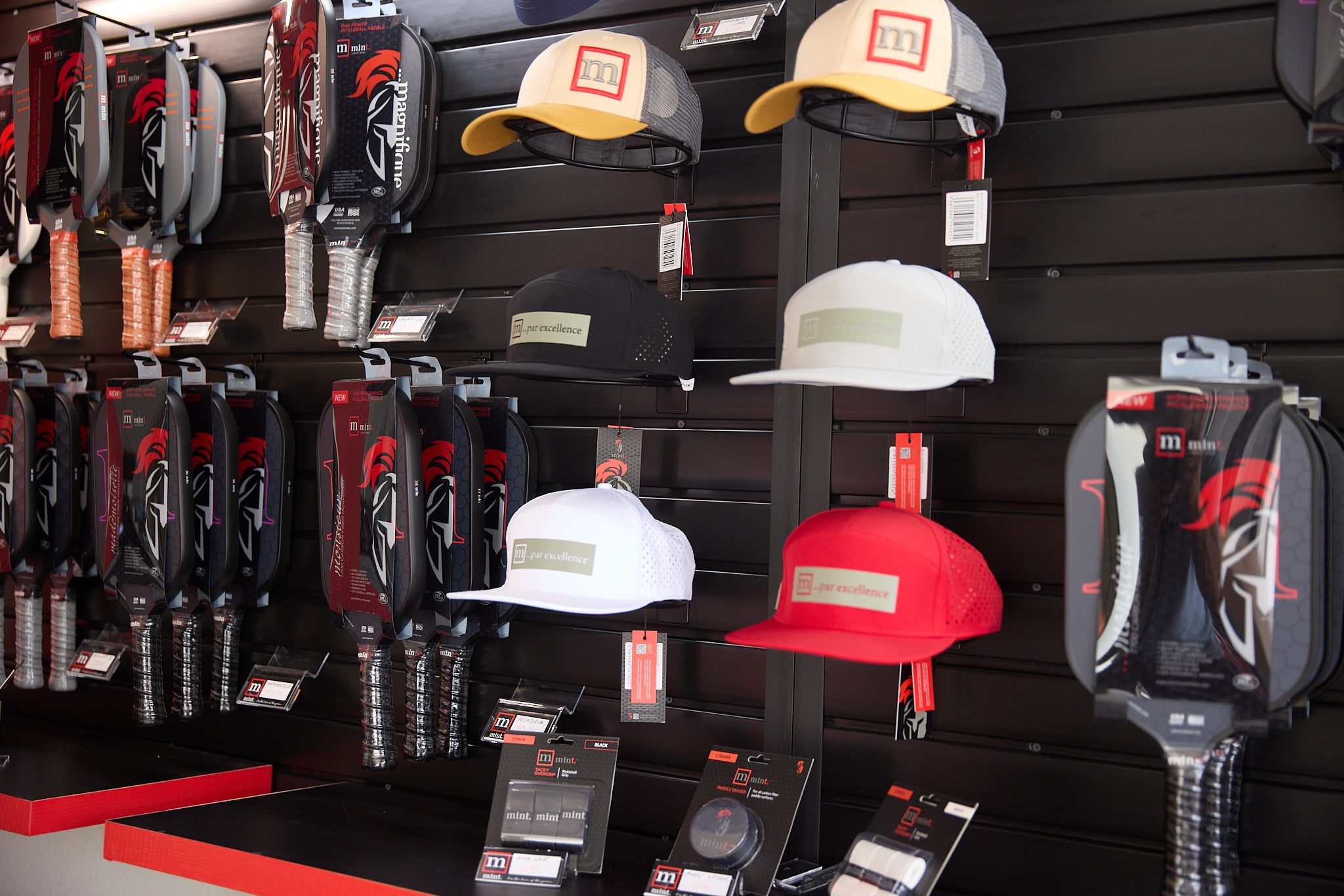 Display of various hats and accessories on a black wall with red accents.