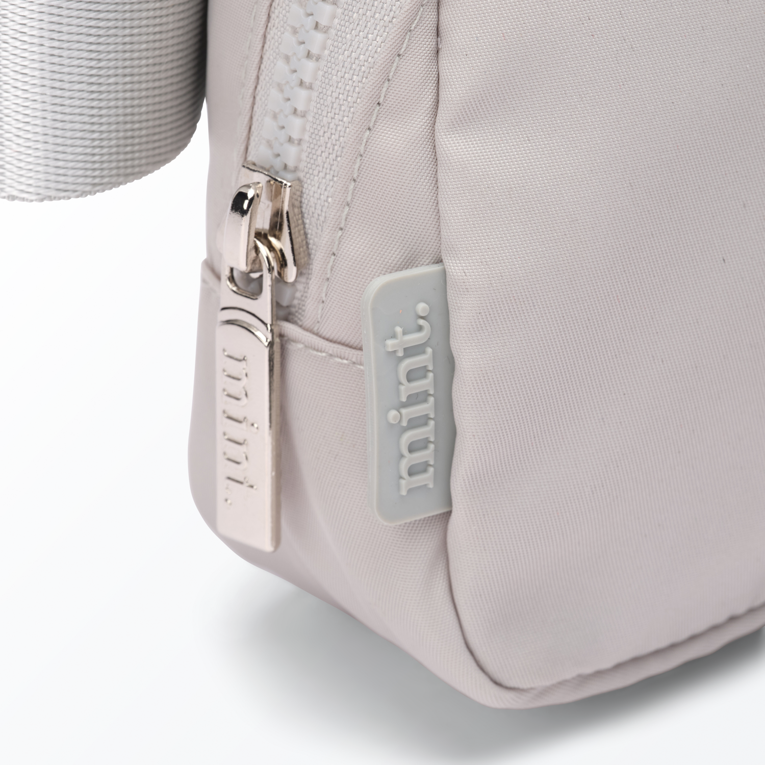 Close-up of a gray-colored Mint Sport belt bag with a zipper on a white background