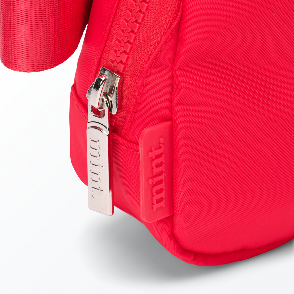 Close-up of a red-colored Mint Sport belt bag with a zipper on a white background