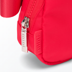 Close-up of a red-colored Mint Sport belt bag with a zipper on a white background