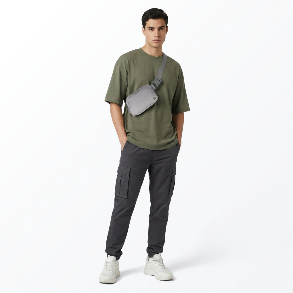 Man wearing a green t-shirt, gray cargo pants, gray Mint Sport belt bag, and white shoes on a white background