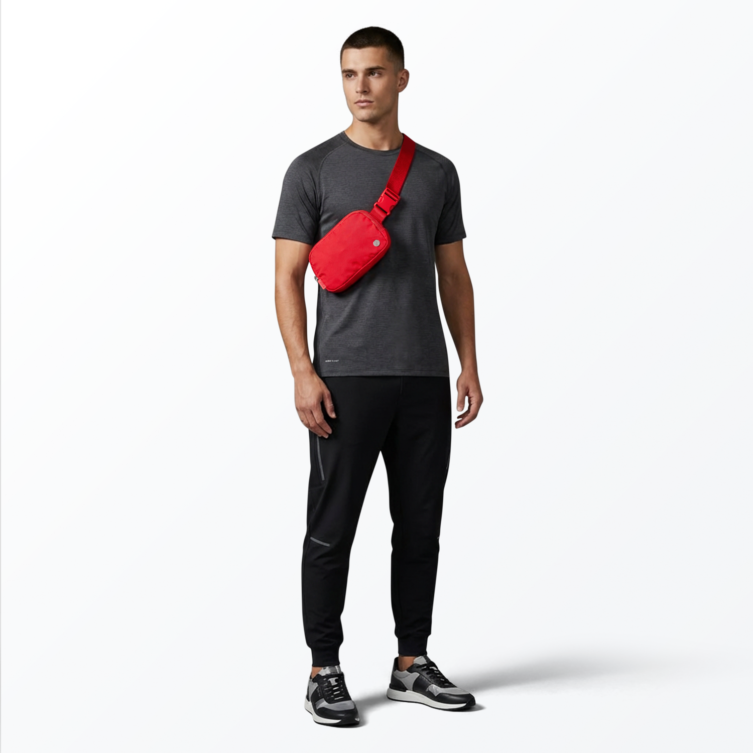 Man wearing a gray t-shirt, black pants, and black sneakers with a red Mint Sport belt bag on a white background