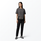 Woman wearing a gray t-shirt, black pants, gray Mint Sport belt bag, and gray shoes on a white background