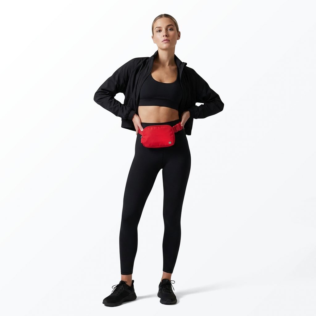 Woman wearing a black athletic outfit with a red Mint Sport belt bag on a white background