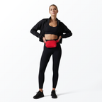 Woman wearing a black athletic outfit with a red Mint Sport belt bag on a white background