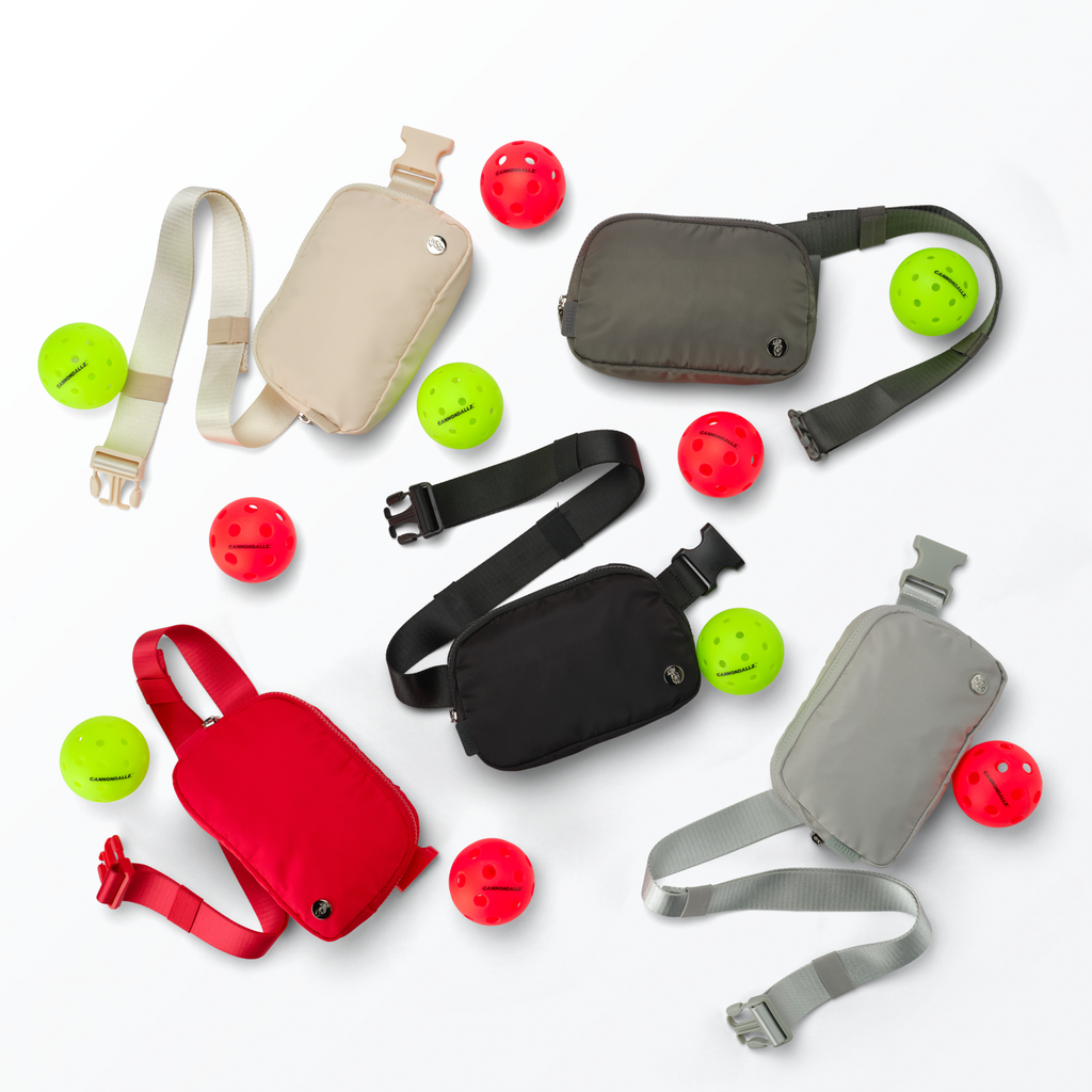 Various Mint Sport belt bags in different colors with red indoor and green outdoor Cannonballz pickleball balls on a white background