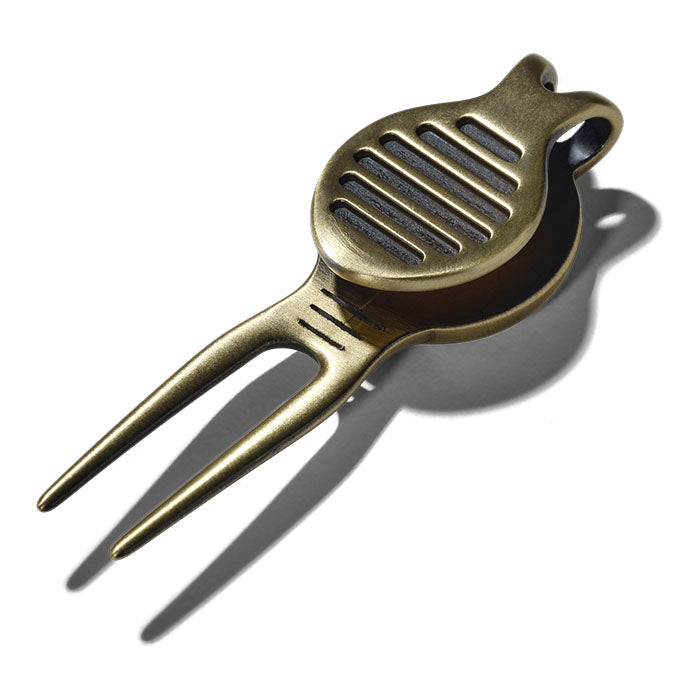 Bronze-colored golf divot tool on a white background