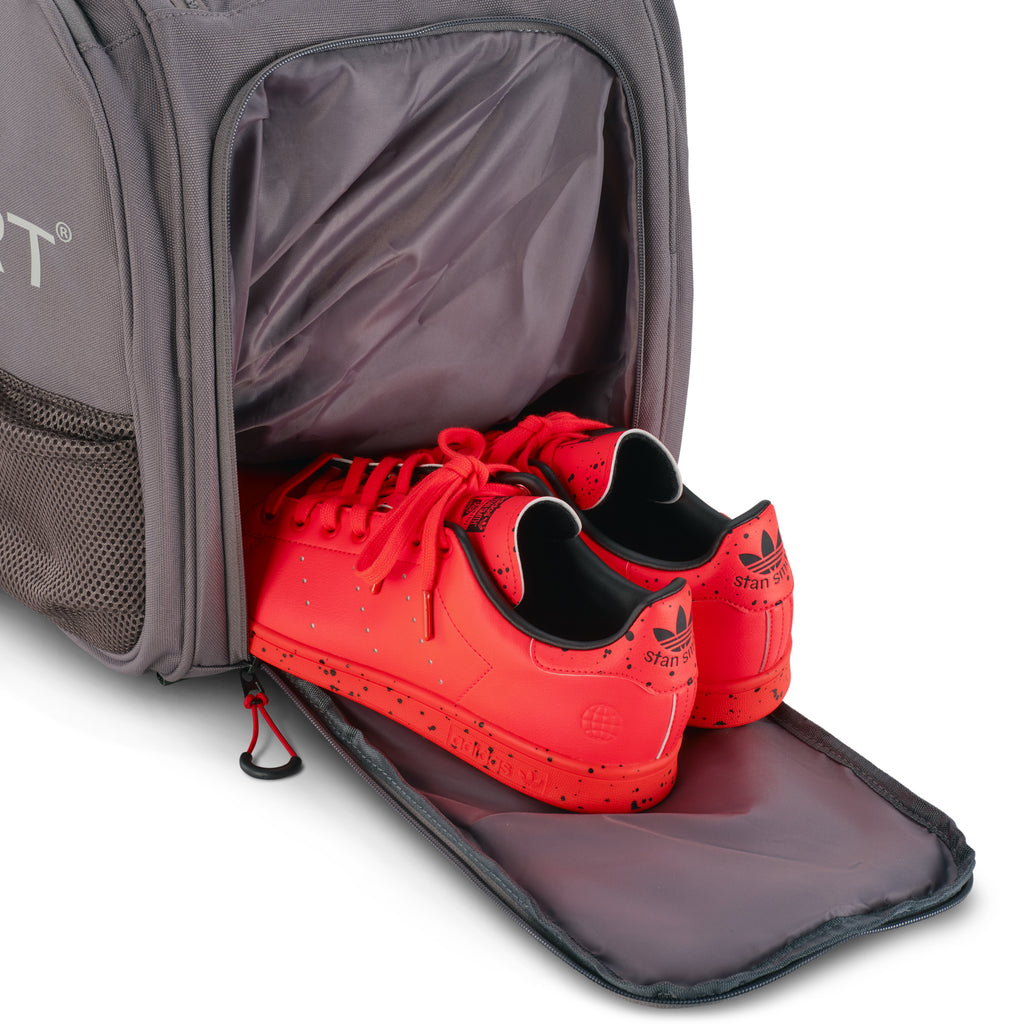 Unleash Tournament Bag in Gray, court shoes coming out of the bottom shoe compartment