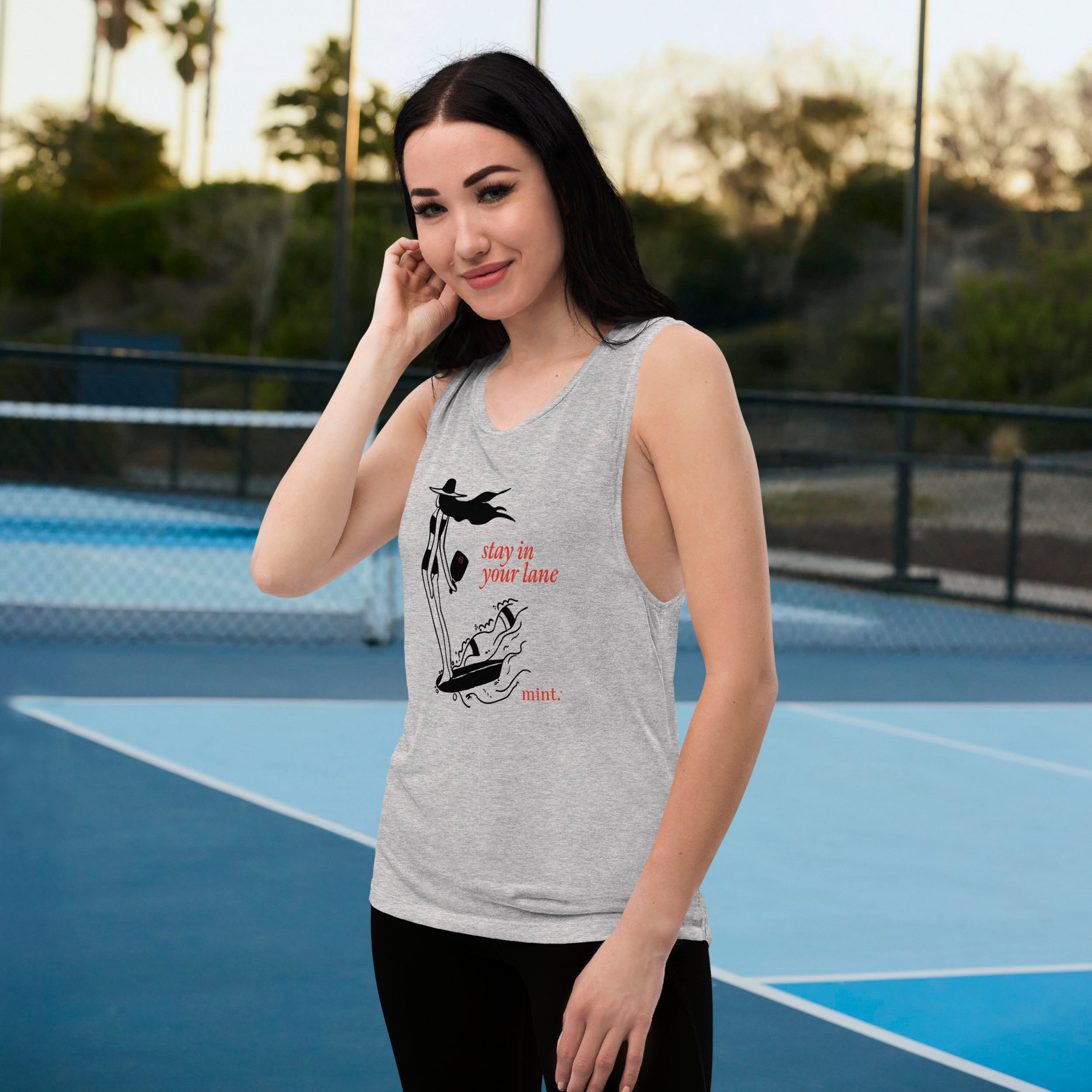 Woman wearing a gray tank top with a graphic design on an outdoor court