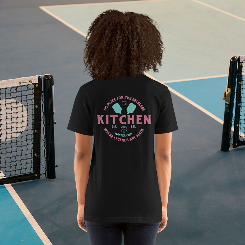 Person wearing a black t-shirt with text and graphics on the back, standing on a tennis court.