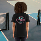 Person wearing a black t-shirt with text and graphics on the back, standing on a tennis court.