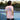Person wearing a pink t-shirt with a graphic design on the back, standing on a tennis court.