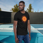 Man wearing a black t-shirt with a red and yellow graphic design standing in front of a pool.